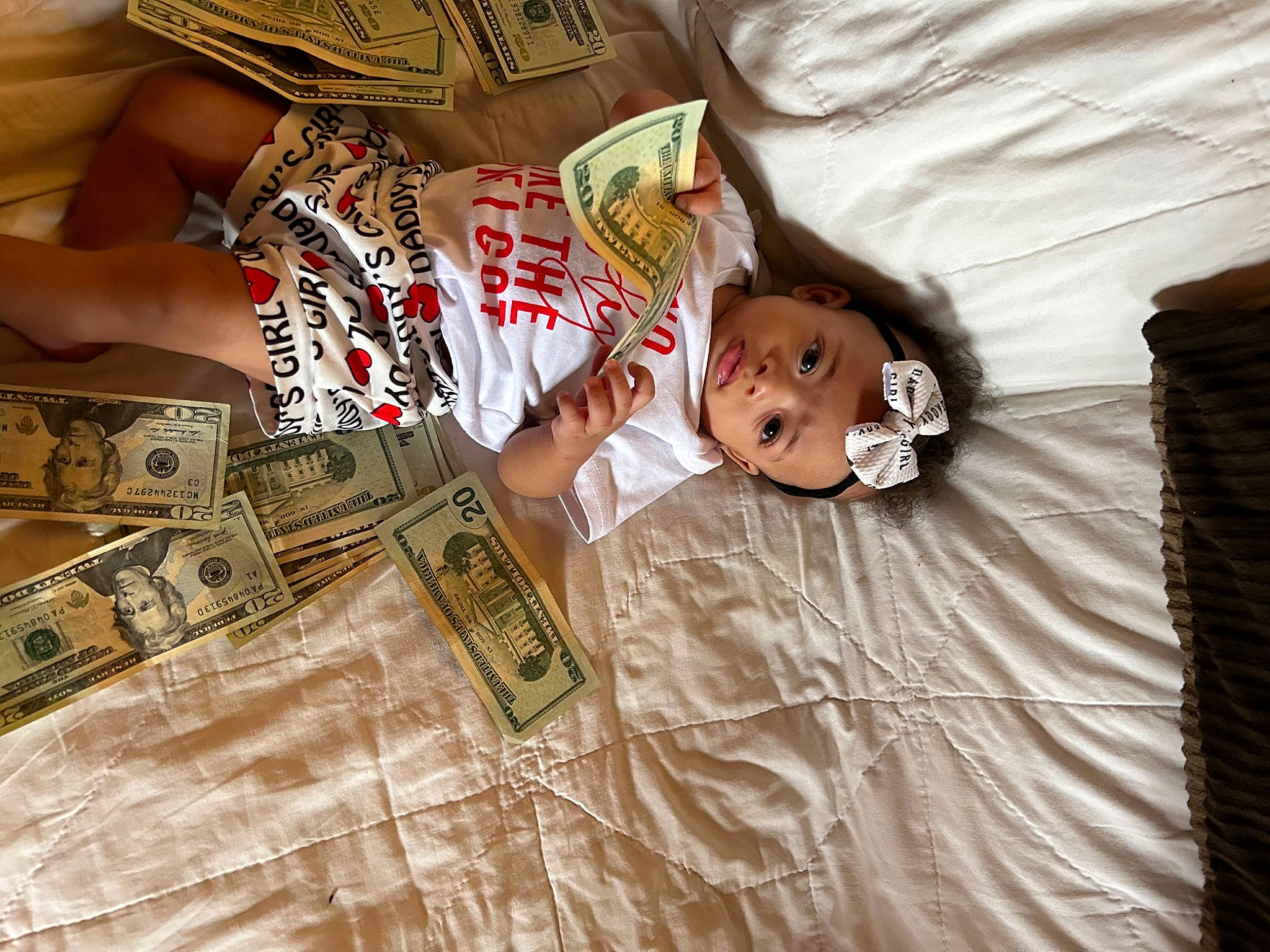 Ocean is registered to the contest to win money with this photo: baby, baby_toddler_clothing, banknote, bedding, brown, cash, comfort, currency, flooring, hardwood, headwear, linens, money, money_handling, pattern, person, room, saving, sleeve, textile
