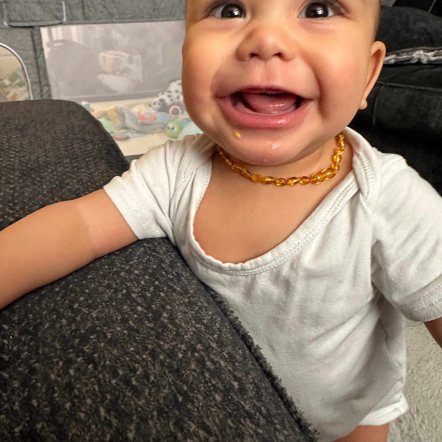 Dion is registered to the contest to win money with this photo: accessories, baby, babylaughing, bodypart, clothing, couch, face, furniture, happy, head, homedecor, jewelry, laughing, mouth, necklace, person, photography, portrait, smile, t_shirt