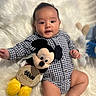 baby, barefoot, checkered_outfit, child, closeup, happy, indoor, infant, mickey_mouse, milestone_card, monthly_milestone, photography, plush_toy, portrait, romper, sitting, smiling, stuffed_animal, white_rug, wide_eyed