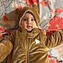baby, child, infant, bear_costume, hood, cute, floral_pattern, blanket, hands, smile, wide_eyes, soft_texture, brown_clothing, portrait, indoor, face, person, baby_outfit, adorable, lying_down