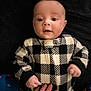 baby, infant, child, clothing, black_and_white, checkered_pattern, hand, adult_hand, ring, portrait, face, eyes, cozy, soft_texture, indoor, cute, looking_at_camera, fingers, sleeves, warm