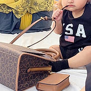 Jazleen joined the competition — help win amazing prizes! toddler, child, face, sitting, black_clothing, handbag, purse, curious, indoor, people, background, accessory, young_child, chewing, brown_bag, black_gloves, person, portrait, casual, cute