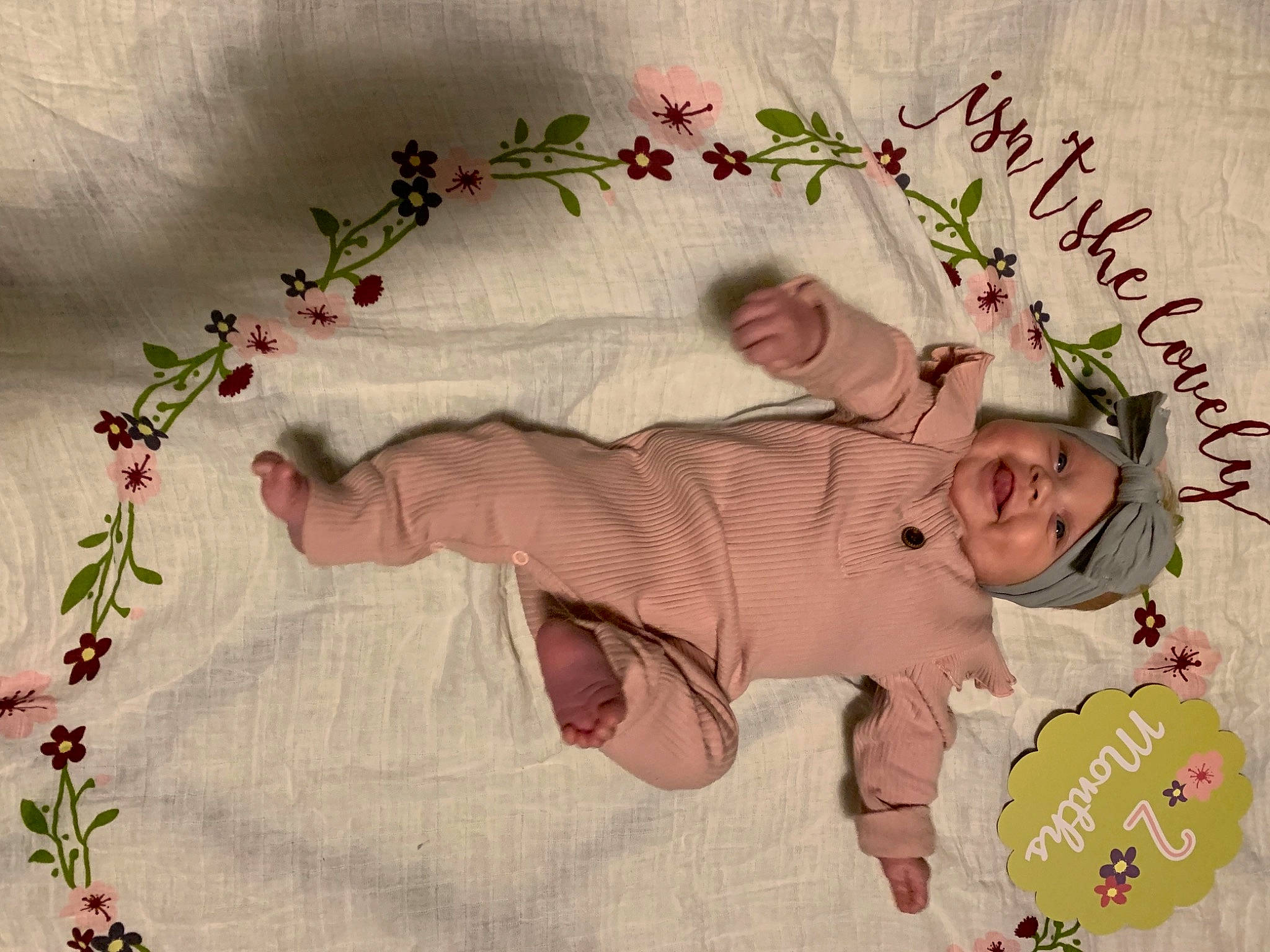 Holland is registered to the contest to win money with this photo: artificial_flower, baby, baby_toddler_clothing, craft, creative_arts, floral_design, happy, headwear, linens, mouth, needlework, nose, peach, pedicel, person, petal, pink, skin, textile