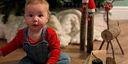 Seren is registered to the contest to win money with this photo: baby, child, blocks, wooden_floor, christmas_tree, holiday_decorations, reindeer, santa_hat, wood_logs, tape_measure, level_tool, indoor, floor_toys, cute, festive, seasonal, decorations, smiling, playful, overalls
