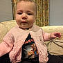 Seren joined the competition — help win amazing prizes! baby, child, knitted_cardigan, pink, iron_maiden_tshirt, couch, indoor, curtains, portrait, sitting, face, clothing, cute, warm_lighting, person, young_child, casual, home, relaxed, infant