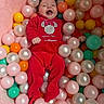 Mya a rejoint le concours — aidez-le/la à gagner de superbes lots ! baby, child, ball_pit, red_clothing, minnie_mouse, smiling, happy, colorful, toys, play, indoor, cute, infant, pink, orange, yellow, teal, white, soft, fun