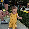 adult, aviary, baby, birds, child, feeding, greenery, hand, nature, outdoor, parent, playground, portrait, smiling, snack, standing, sundress, toddler, walking, yellow_outfit