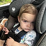 baby, blonde_hair, car, car_seat, child, clothing, eyes, face, indoors, passenger, portrait, safety_harness, seatbelt, serious_expression, sitting, toddler, travel, trees, vehicle, window
