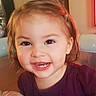 adorable, brown_hair, camera, candid, child, close_up, eyes, face, gap_tooth, girl, happy, home, indoors, portrait, purple_shirt, sitting, smiling, teeth, toddler, warm_lighting