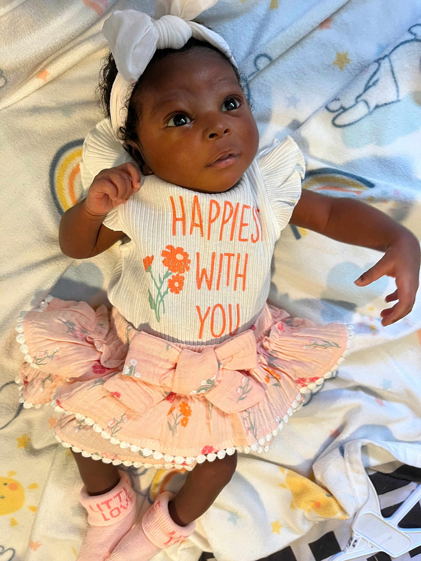 Alina is registered to the contest to win money with this photo: baby, infant, child, cute, headband, bow, skirt, socks, blanket, pattern, floral, shirt, text, lying_down, indoors, soft, pastel_colors, expression, portrait, person