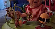 Ronin is registered to the contest to win money with this photo: baby, child, infant, smiling, laughing, portrait, indoor, living_room, activity_center, toy, playtime, striped_shirt, red_shirt, seated, happy, face, furniture, colorful, home, photography