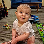 Ronin joined the competition — help win amazing prizes! baby, child, infant, sitting, smiling, portrait, face, indoors, living_room, carpet, couch, toy, toy_truck, play_mat, blanket, onesie, red_ball, colorful, happy, family_home