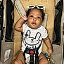 Kiara joined the competition — help win amazing prizes! baby, black_hair, child, clothing, comfort, curly_hair, cute, fabric, face, hand, indoor, infant, keys, onesie, person, portrait, seatbelt, smile, stroller, sunglasses