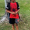 backpack, black_shoes, boy, building, casual, child, daytime, grass, nature, outdoor, person, shorts, spider_man, standing, street, suburban, tree, tshirt, vehicle, young