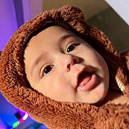 Carlos is registered to the contest to win money with this photo: baby, child, face, hood, brown, fur, closeup, curious, eyes, mouth, expression, indoor, soft, warm, clothing, portrait, cute, infant, fluffy, lighting