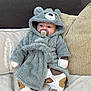 Louie-George is registered to the contest to win money with this photo: baby, child, pacifier, robe, bear_hood, couch, pillow, blanket, clothing, indoors, cute, infant, soft_texture, sleepwear, relaxing, portrait, young_child, face, cozy, seated