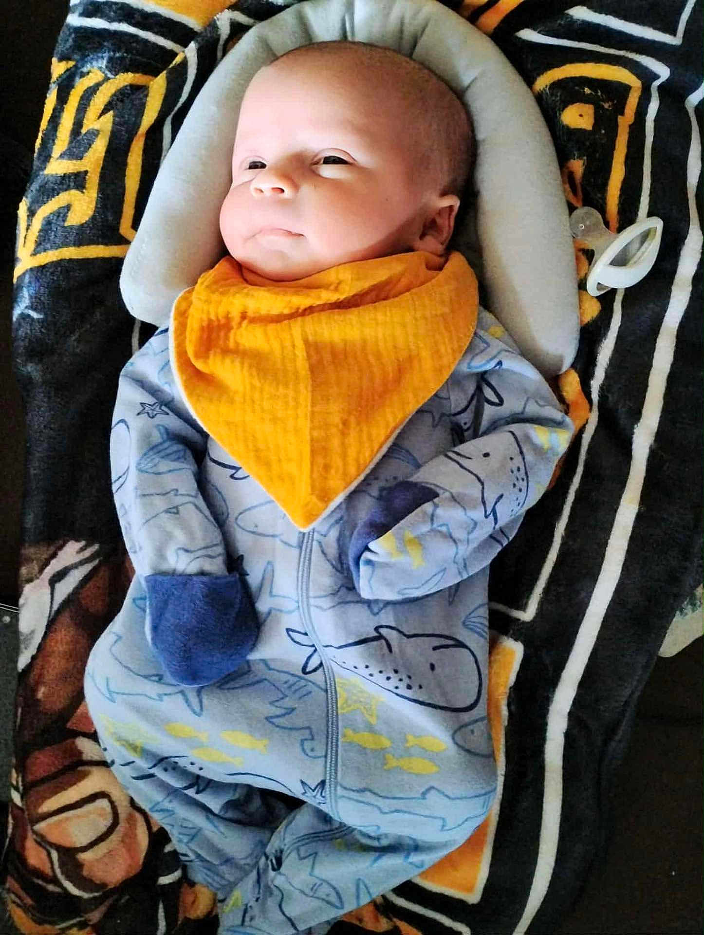 Jensen joined the competition — help win amazing prizes! baby, infant, blanket, pacifier, onesie, bib, blue_clothing, orange_bib, face, head_support, patterned_blanket, lying_down, cute, cozy, child, newborn, sleepwear, soft_toys, indoor, resting