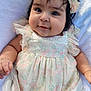 baby, infant, child, face, smile, flower_headband, dress, floral_pattern, cute, soft_blanket, chubby_cheeks, portrait, closeup, happy, adorable, young_child, skin, hand, eyes, person