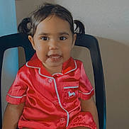 Kytaiviah is registered to the contest to win money with this photo: black_chair, buttoned_shirt, chair, child, clothing, cute, face, happy, indoor, person, pigtails, portrait, red_pajamas, seated, shorts, skin, smile, toddler, wall, young_child