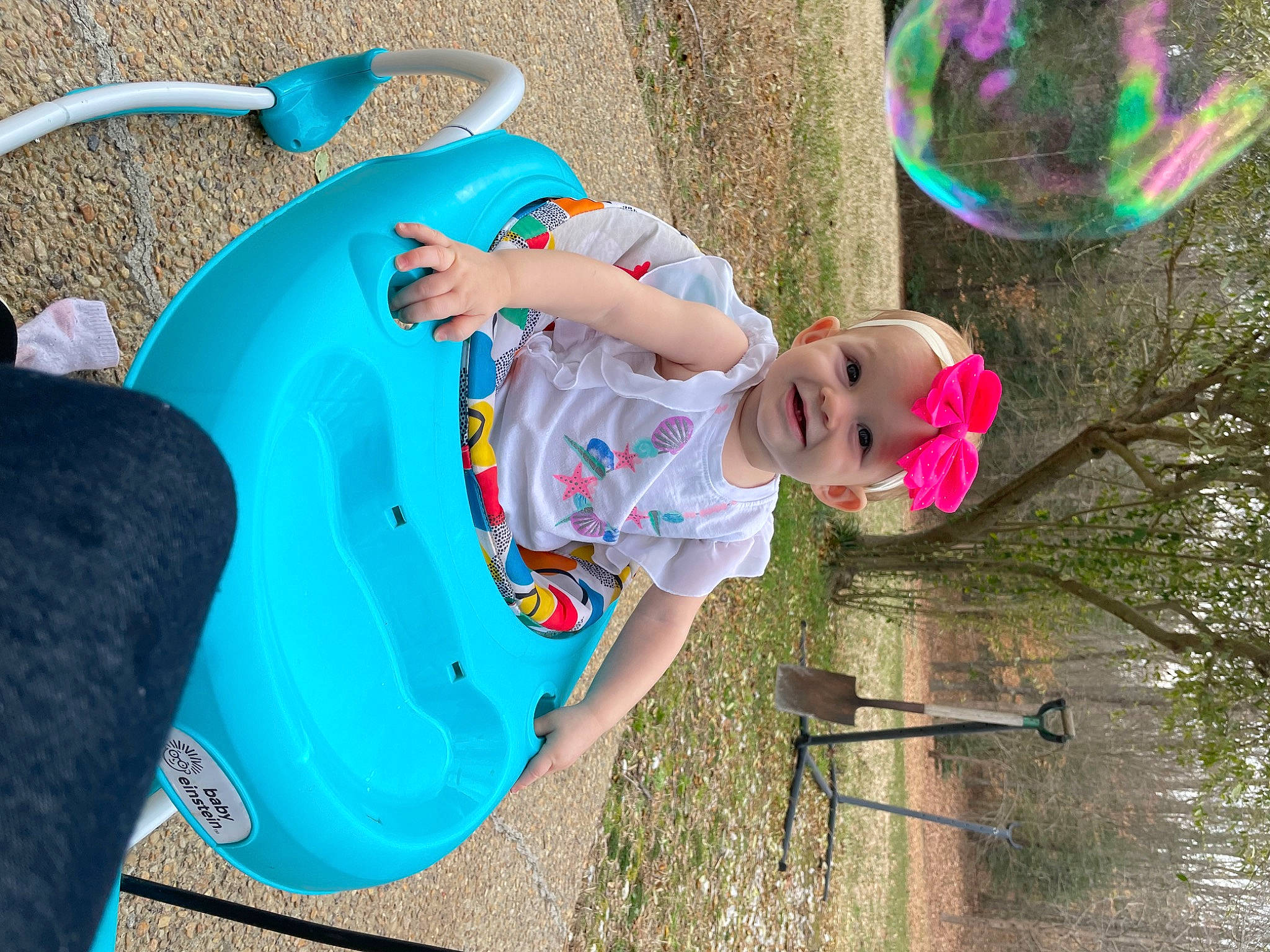 Norea is registered to the contest to win money with this photo: baby, baby_toddler_clothing, child, electric_blue, fun, grass, happy, hat, headwear, joy, leisure, magenta, outdoor_play_equipment, people_in_nature, person, pink, plant, play, recreation, sitting