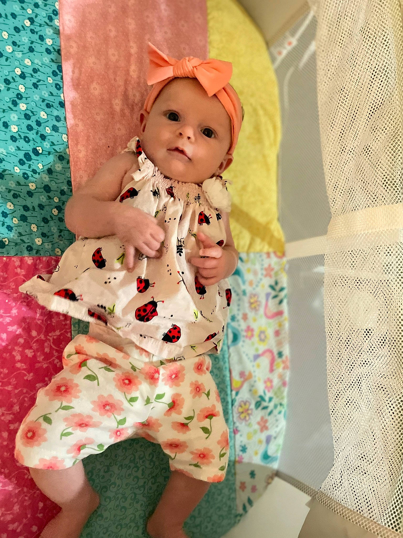 Norea is registered to the contest to win money with this photo: baby, baby_toddler_clothing, baby_toys, child, collar, costume, doll, headwear, linens, magenta, nightwear, outerwear, pattern, peach, person, pink, room, sleeve, smile, toddler