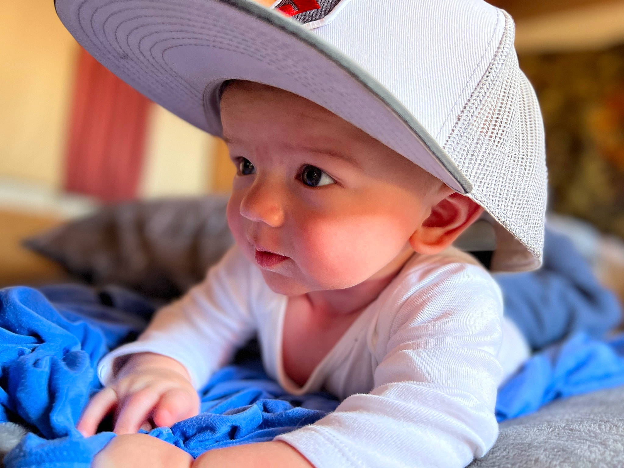 Gregory is registered to the contest to win money with this photo: baby, baby_toddler_clothing, blue, cap, child, chin, comfort, electric_blue, face, fashion_accessory, fun, happy, hat, headgear, headwear, leisure, person, sitting, skin, smile