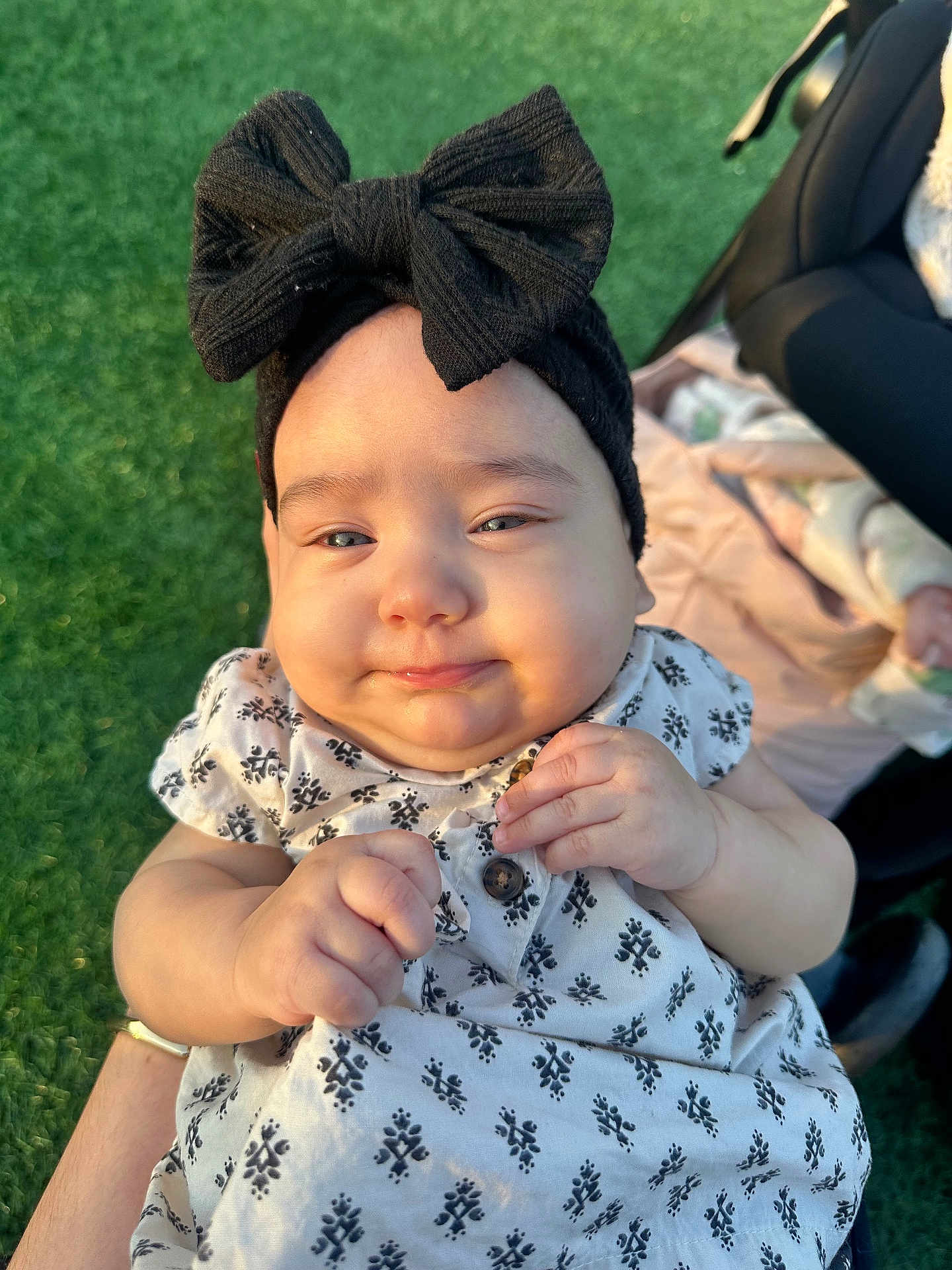 Zhoe is registered to the contest to win money with this photo: baby, infant, child, headband, bow, clothing, dress, hand, face, outdoor, grass, person, cute, smile, sunlight, skin, holding, portrait, happy, young