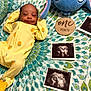 Jelani joined the competition — help win amazing prizes! baby, newborn, smiling, yellow_onesie, bedspread, ultrasound_photo, plush_toy, one_month, infant, lying_down, patterned_bedspread, cute, happy, child, portrait, indoors, soft_toy, sleepwear, baby_milestone, resting