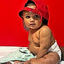 Milah joined the competition — help win amazing prizes! baby, child, red_cap, diaper, curious, sitting, indoor, cute, infant, skin, expression, face, headwear, bare_chest, soft_cloth, white_surface, red_background, portrait, closeup, person