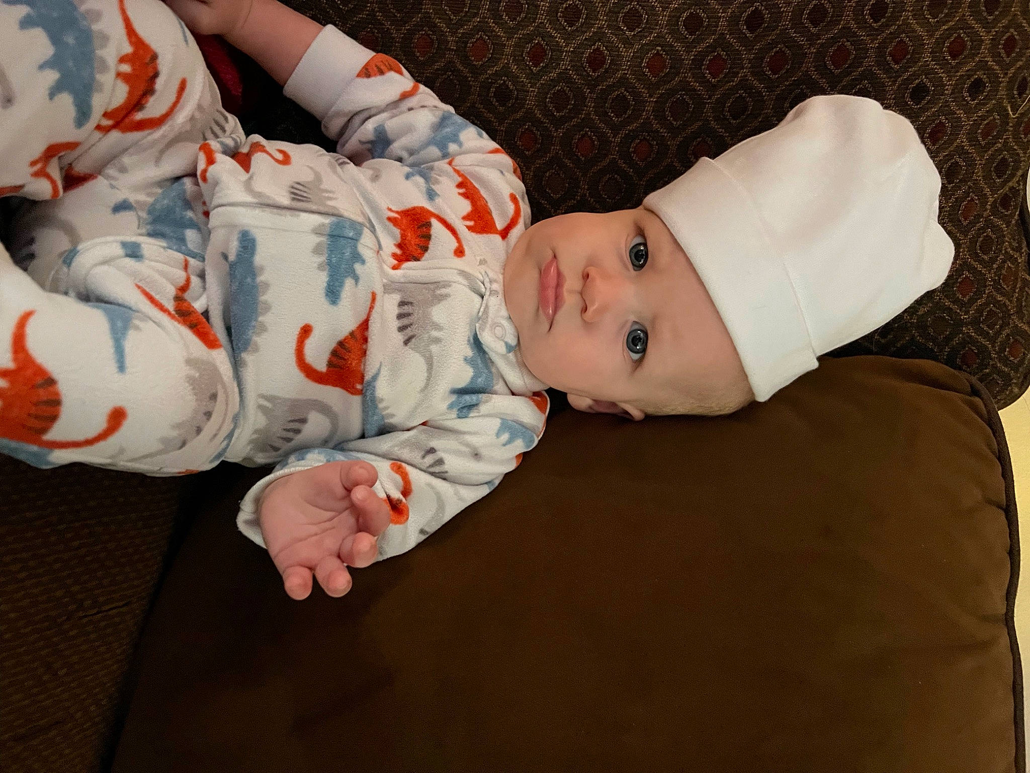 Wylie is registered to the contest to win money with this photo: baby, baby_products, baby_toddler_clothing, carmine, cheek, child, comfort, hat, head, headwear, human_body, linens, pattern, person, room, sitting, skin, sleeve, toddler