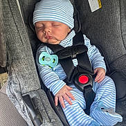 Oaklan is registered to the contest to win money with this photo: baby, sleeping, car_seat, pacifier, striped_clothing, blue_hat, infant, child, seatbelt, safety, cute, newborn, hand, footwear, plush_toys, gray, fabric, indoor, person, resting
