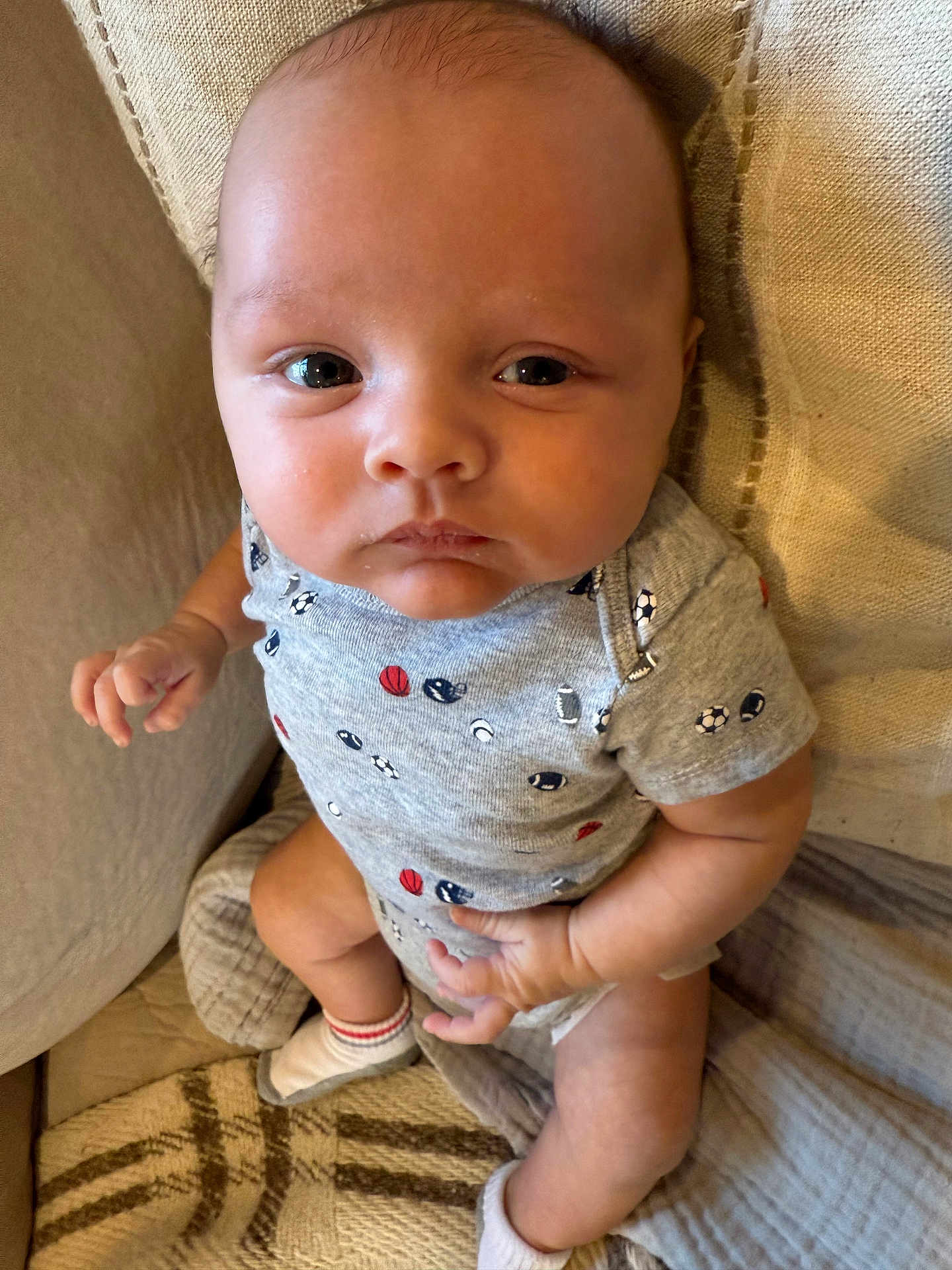 Oaklan joined the competition — help win amazing prizes! baby, blanket, child, comfort, couch, cute, expression, eyes, fabric, face, hands, indoor, infant, legs, onesie, portrait, sitting, skin, socks, soft