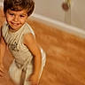 child, toddler, smiling, sitting, portrait, indoor, couch, sofa, furniture, brown_hair, white_clothing, shirt, pants, face, eyes, teeth, home, cozy, photography, happy