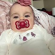 Milla joined the competition — help win amazing prizes! baby, pacifier, headband, flower, pillow, indoors, face, child, clothing, sweater, pink, white, red, sitting, portrait, person, cute, infant, home, relaxing