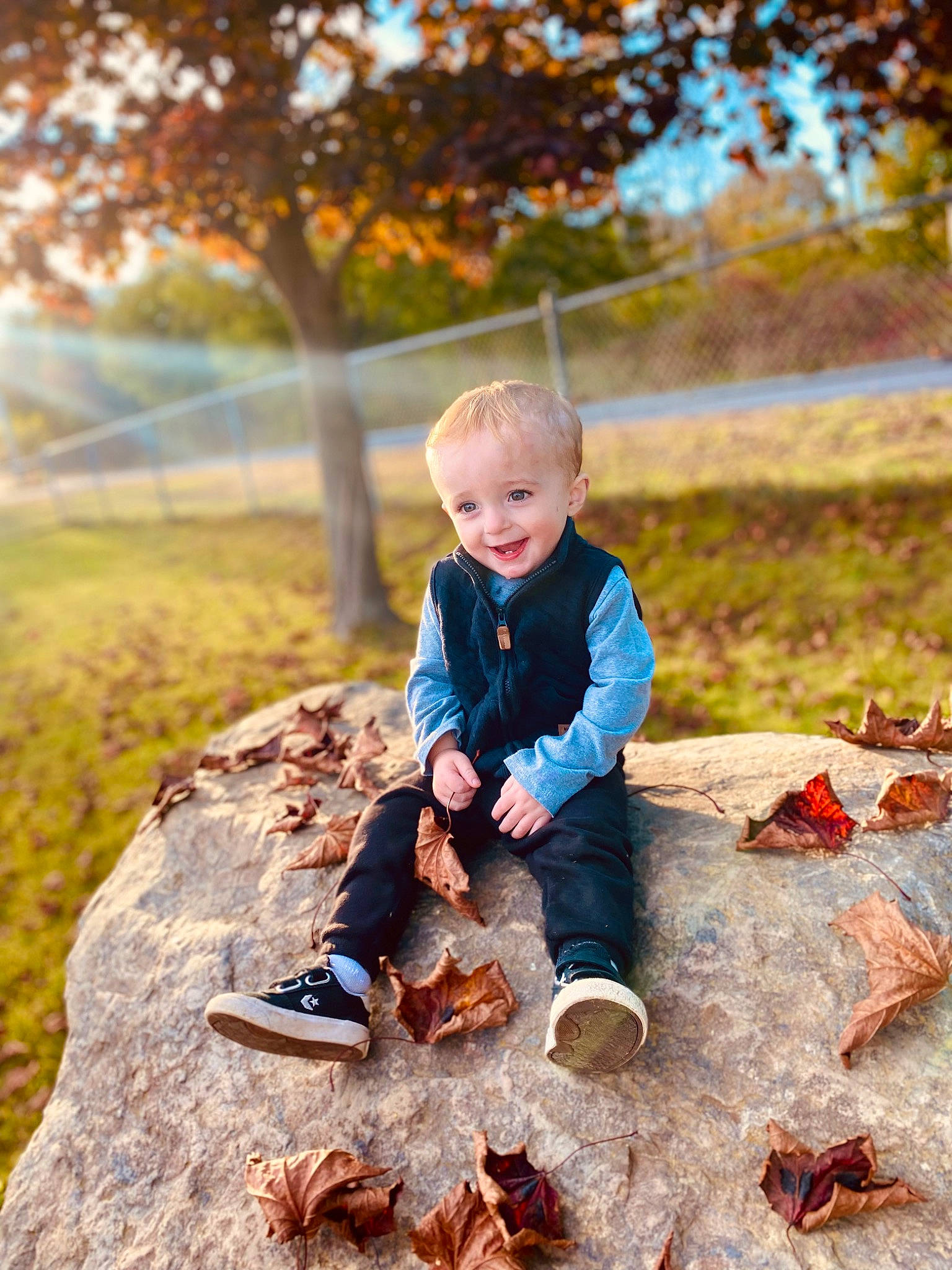 Nikolas is registered to the contest to win money with this photo: baby, boot, branch, child, deciduous, flash_photography, fun, grass, happy, joy, landscape, leaf, leg, leisure, people_in_nature, person, plant, sitting, smile, toddler