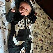 Quentin is registered to the contest to win money with this photo: baby, infant, hoodie, nike, black_clothing, lying_down, blanket, animal_print, lion, giraffe, elephant, zebra, cute, face, expression, footwear, socks, indoor, child, young