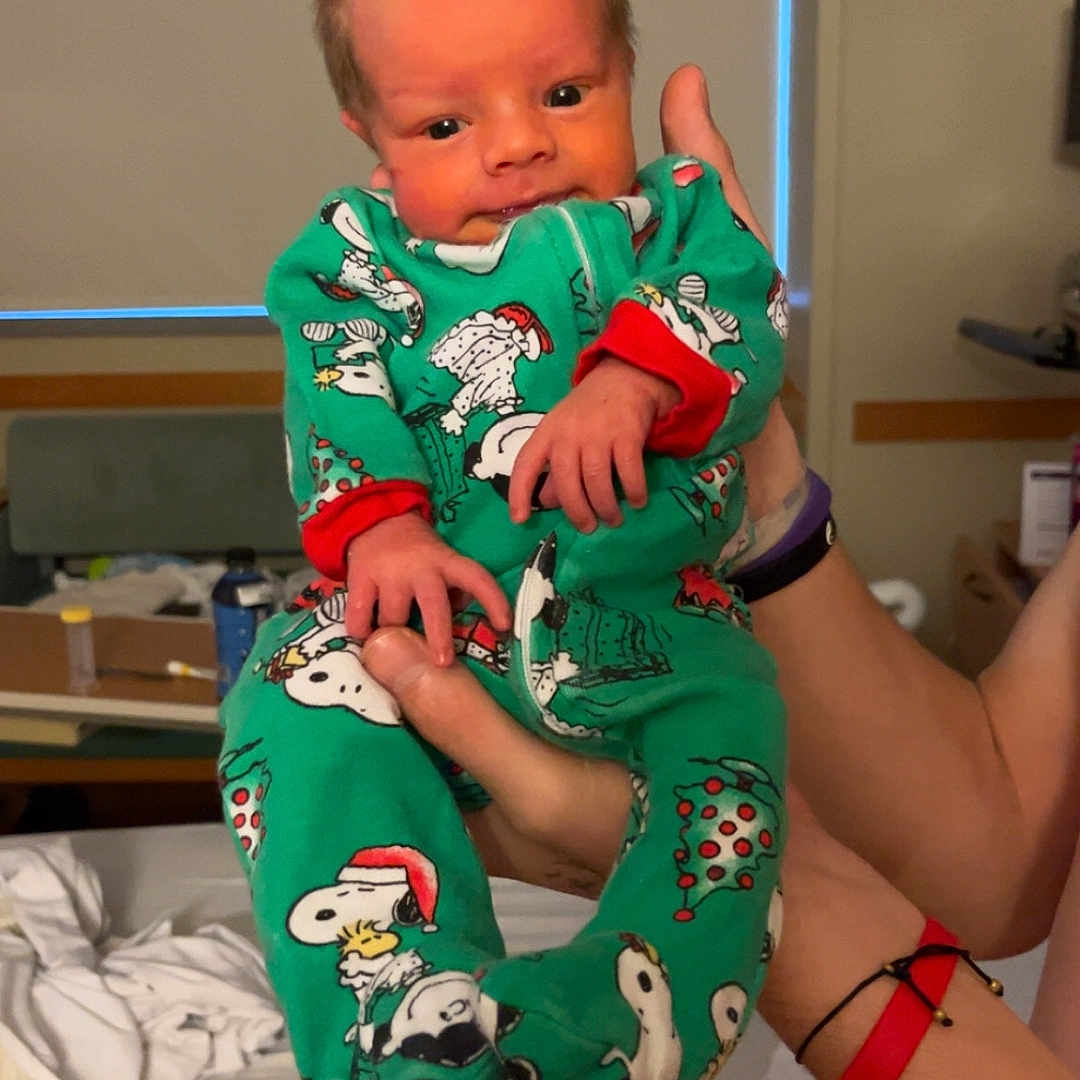 Quentin joined the competition — help win amazing prizes! adult, baby, bed, blanket, child, cute, green_clothing, hand, holding, home, indoor, infant, newborn, pajamas, person, portrait, room, sleepwear, snoopy, soft_lighting