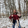 Regan is registered to the contest to win money with this photo: woman, dog, snow, forest, trees, winter, outdoor, sweater, holding, smile, canine, nature, cold, leafless_trees, casual_clothing, happy, animal, pet, portrait, daylight