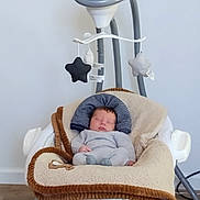 Myles is registered to the contest to win money with this photo: baby, newborn, sleeping, baby_swing, blanket, toy, star_toy, plush, cozy, infant, clothing, head_support, indoor, floor, wooden_floor, resting, child, peaceful, comfort, nursery
