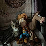 cat, tabby_cat, plush_toy, woody_doll, horse_plush, blanket, patterned_blanket, indoor, furniture, sofa, pet, animal, cute, relaxed, toy_story, soft_lighting, cozy, nostalgic, stuffed_animal, companion