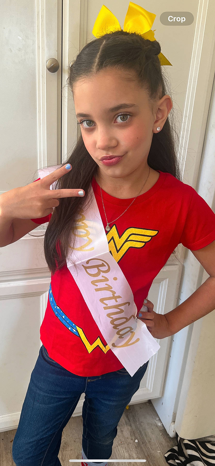 Mia is registered to the contest to win money with this photo: accessories, bodypart, child, clothing, door, face, female, finger, girl, hand, head, jeans, jewelry, longsleeve, necklace, pants, person, sash, sleeve, t_shirt