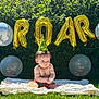 baby, child, grass, blanket, balloons, party_hat, confetti, celebration, outdoor, sunlight, greenery, milestone, cute, funny_face, half_birthday, six_months, smiling, sitting, summer, festive