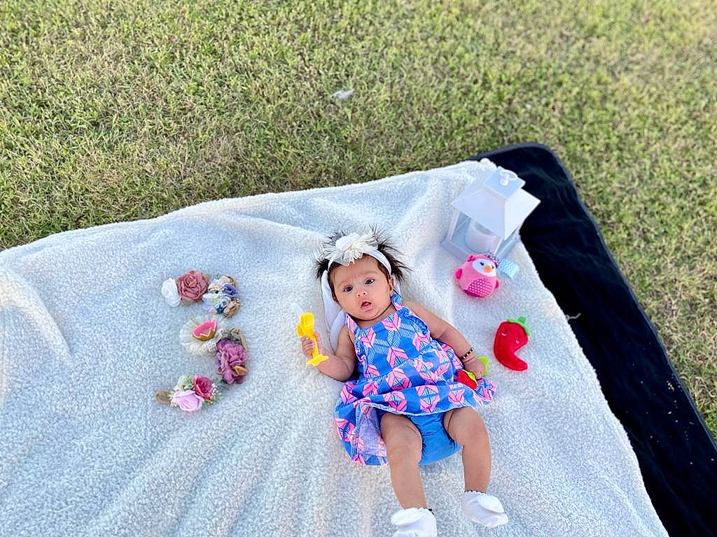 Sadhika is registered to the contest to win money with this photo: art, baby, baby_products, baby_toddler_clothing, child, fashion_accessory, grass, headgear, headwear, leisure, linens, magenta, pattern, person, petal, pink, recreation, sleeve, surprise, t_shirt
