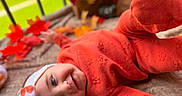 Aria joined the competition — help win amazing prizes! baby, infant, child, portrait, lying_down, orange_outfit, hat, autumn, leaves, blanket, indoor, cozy, warm_colors, face, eyes, smiling, photography, seasonal, soft_focus, home_decor