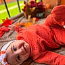 baby, infant, child, portrait, lying_down, orange_outfit, hat, autumn, leaves, blanket, indoor, cozy, warm_colors, face, eyes, smiling, photography, seasonal, soft_focus, home_decor