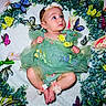 baby, infant, child, portrait, lying_down, floral_dress, green_dress, flower_crown, flowers, butterflies, garden, greenery, leaves, colorful, studio_photography, newborn_photography, wide_eyed, decorative_background, fashion, cute