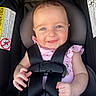baby, infant, child, smiling, happy, portrait, car_seat, seatbelt, safety_harness, pink_clothing, dress, vehicle, indoors, close_up, face, eyes, hands, brown_hair, sitting, automobile