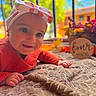 baby, child, infant, portrait, smiling, happy, bow, headband, red_clothing, lying_down, blanket, indoor, window, flowers, decorations, birthday, wooden_sign, colorful, close_up, natural_light