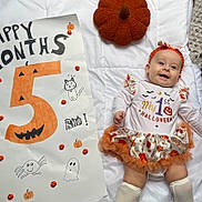 Alayïah participe au concours pour gagner de l'argent avec cette photo : baby, celebration, child, costume, cute, decorations, drawing, face, halloween, headband, infant, lying_down, orange, poster, pumpkin, quilt, skirt, smile, sock, white_background