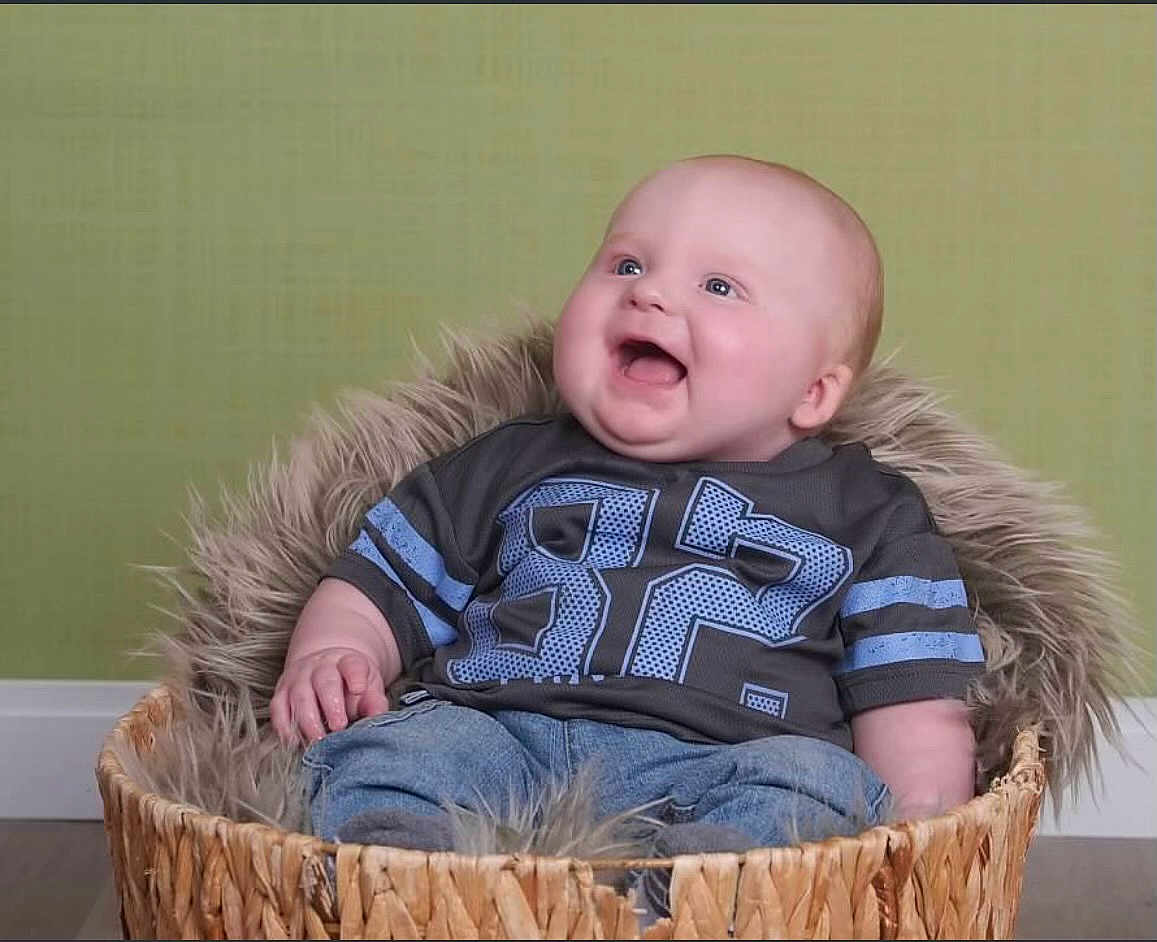 Lucious is registered to the contest to win money with this photo: baby, basket, blue_jeans, clothing, cute, furry, happy, infant, jeans, joyful, looking_up, person, portrait, shirt, sitting, smile, toddler, woven_basket, young_child, indoor